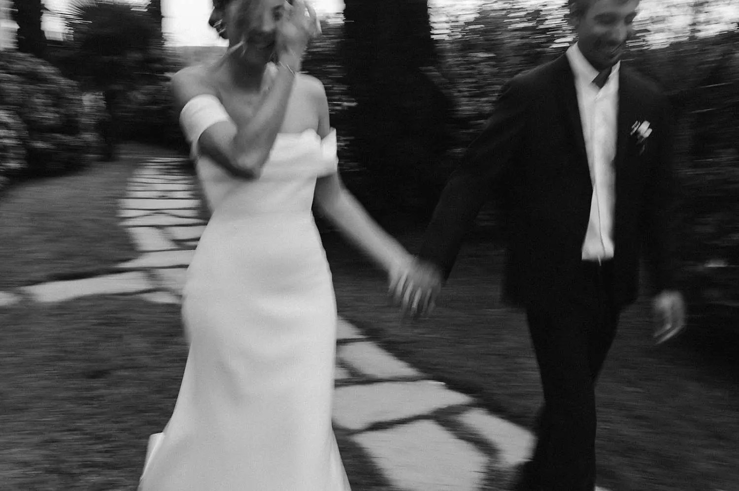 A motion blur candid photo of the bride and groom walking hand in hand, radiating happiness and relaxation. The cropped composition captures their joyful expressions and the carefree movement of their steps, symbolizing the lighthearted and celebratory spirit of the moment.